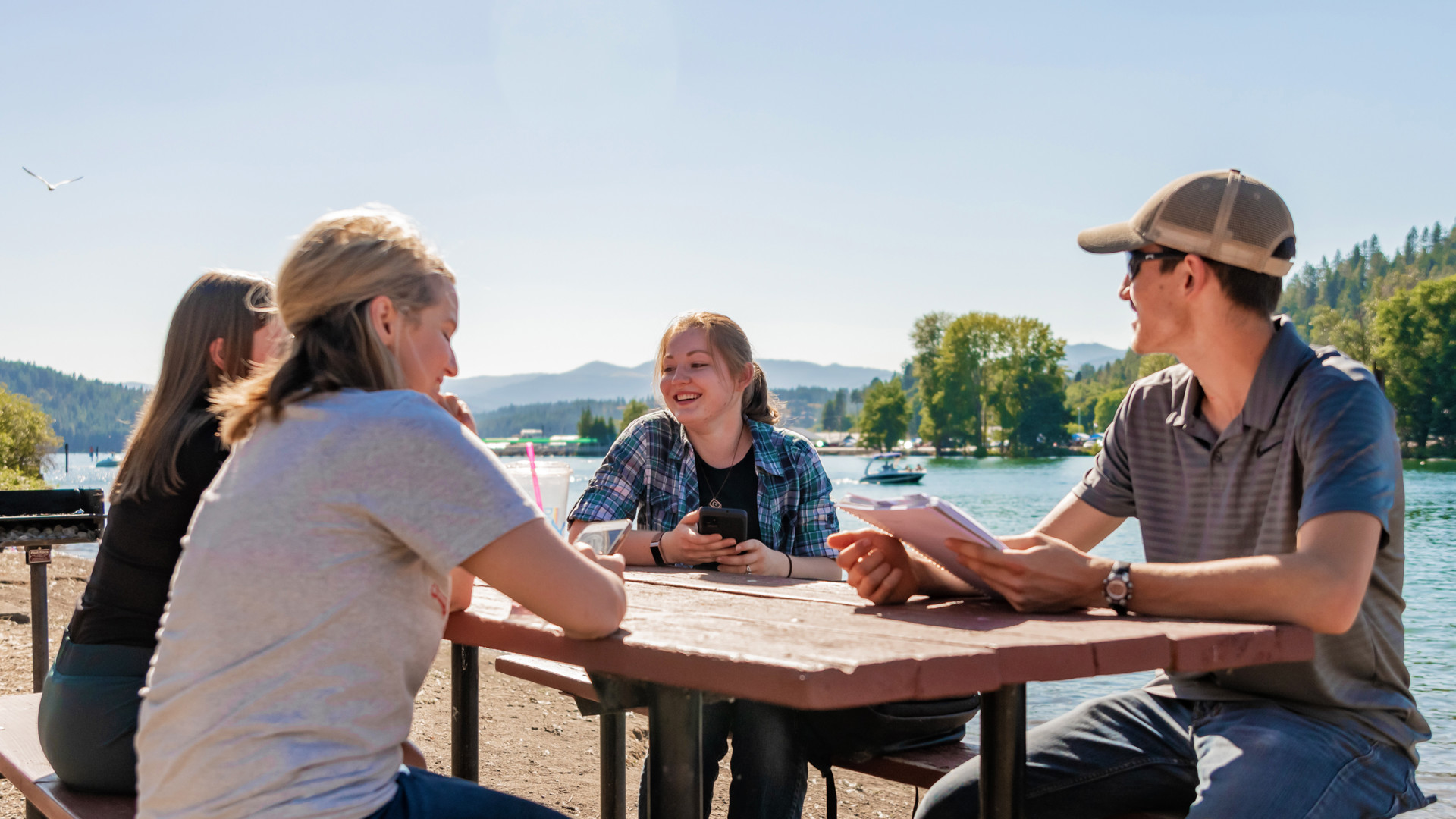 Students sitting outside at a picnic table by lake